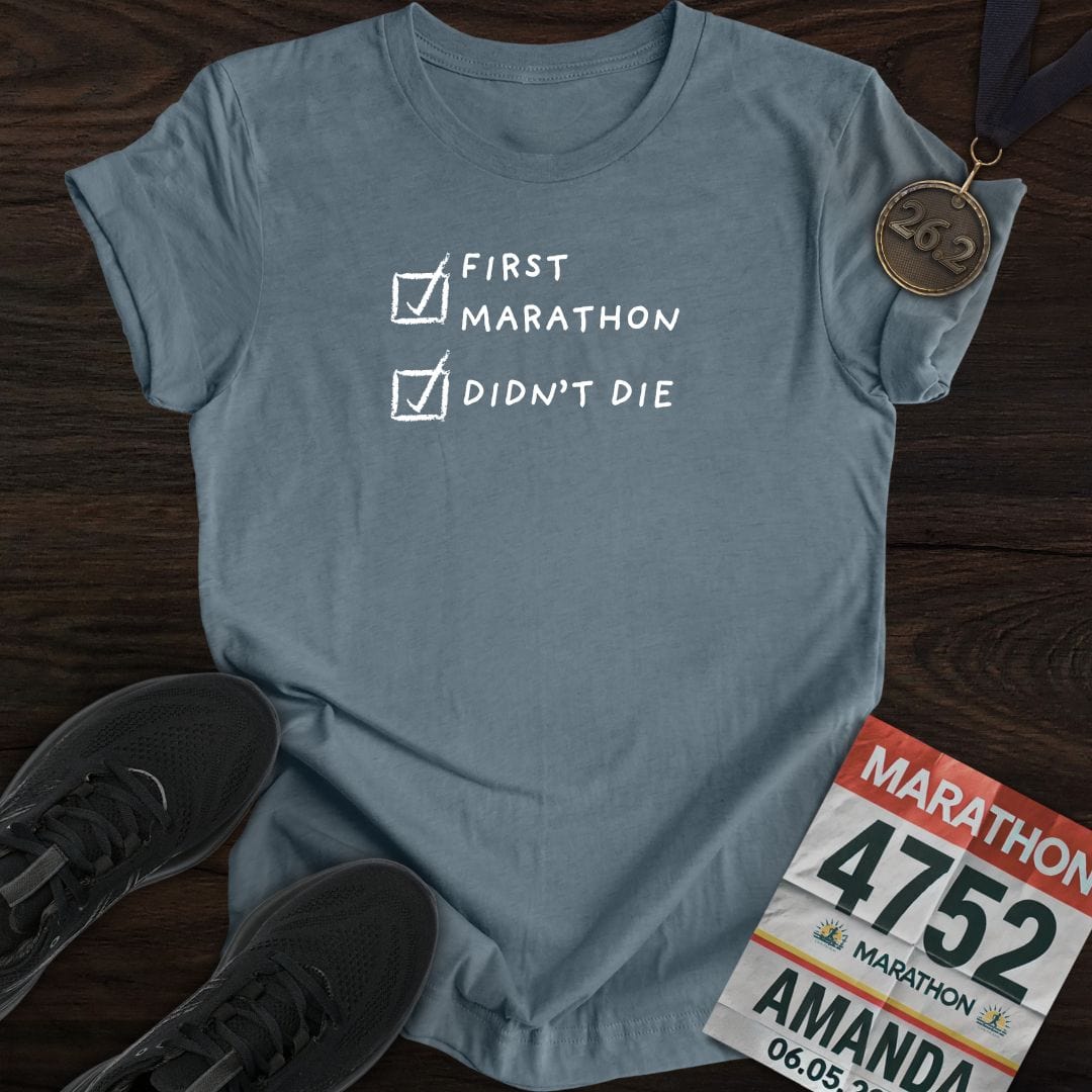 Heather Indigo-colored "First Marathon and Didn't Die" t-shirt, worn by a runner after finishing a race.