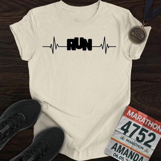 A sand-colored 'Run with Your Heart' t-shirt with a white heartbeat graphic, shown on a flat surface.